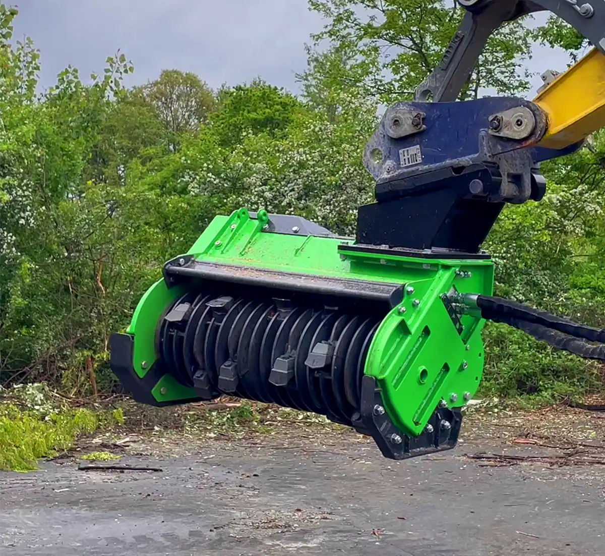 OMEF TE series forestry mulcher on an excavator, showing the fixed-tooth rotor, front pusher bar and hydraulic hose routing